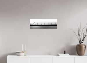 Couple walking on The Pier in Black and White with a bird flying and smokestack in the distance at Grand Haven.