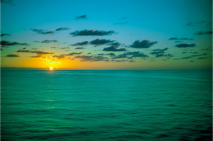 A Caribbean Sunset showcases vibrant colors as the sun sets over tranquil waters, creating a serene atmosphere.