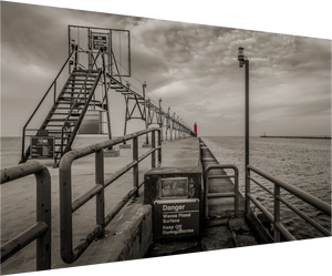 Gloomy black and white scene featuring Big Red on the Grand Haven Pier, showcasing a striking red lighthouse.