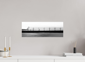 Couple strolls down The Pier in Black and White, with a bird flying by and smoke billowing from a distant smokestack.